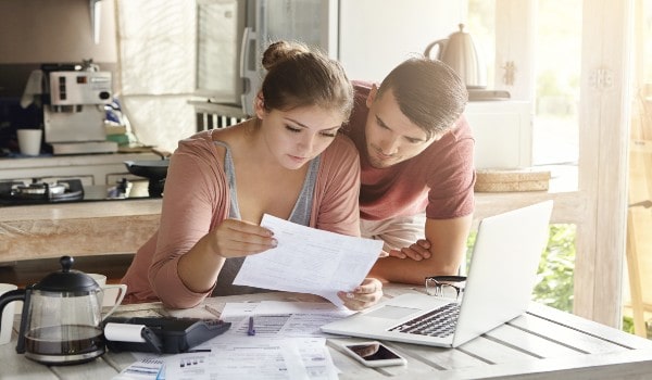 a girl and boy are reading a paper