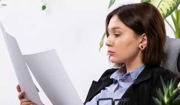 young woman reading some reports while sitting in her office